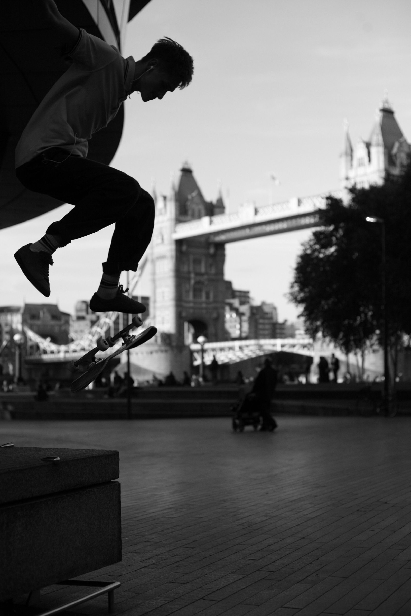 Skateboarder in silhouette jumping in front of Tower Bridge, London, in black and white